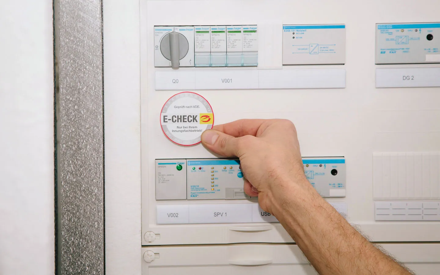 E-CHECK - Mitarbeiter klebt in der Verteilung die E-CHECK Plakette an &middot; Winter Elektro