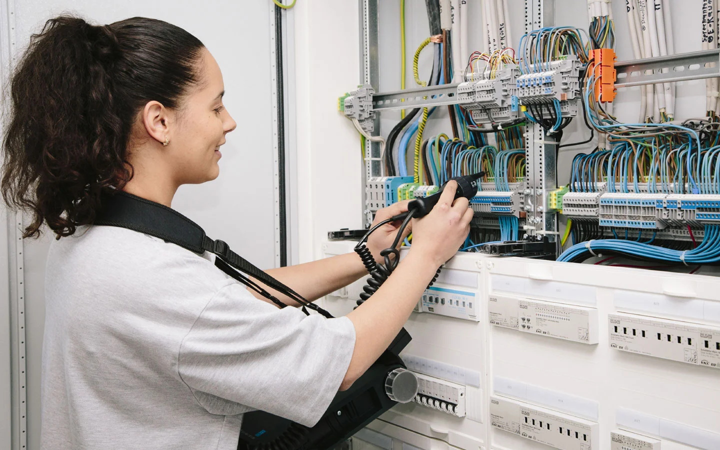 E-CHECK - Mitarbeiterin prüft im Schaltschrank mit einem Meßgerät &middot; Winter Elektro
