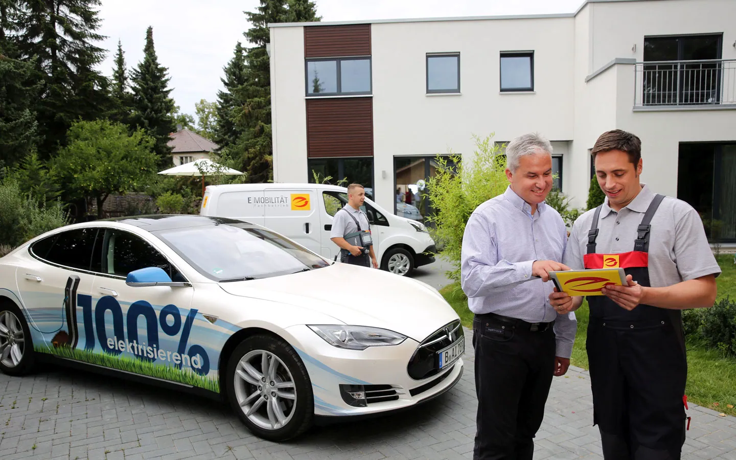 E-Mobilität - Mitarbeiter mit Kunden vor Elektrofahrzeugen 100% elektrisch &middot; Winter Elektro